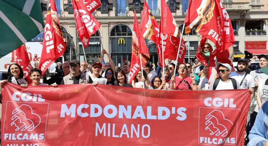 Manifestanti con bandiere rosse chiedono un miglior stipendio McDonald's a Milano.