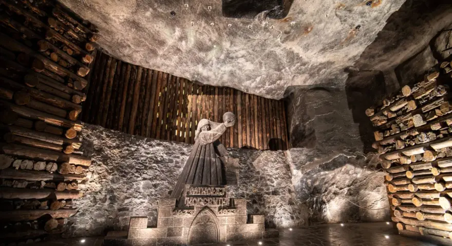 Kopalnia soli Wieliczka ciekawostki: rzeźba górnika Mikołaja Kopernika w solnej komorze, otoczona drewnianymi belkami i solnymi ścianami.
