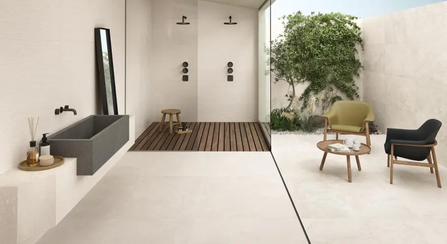 Un bagno moderno con vasca in pietra, doccia a filo pavimento e un'area relax esterna. Il pavimento casa mare crea un'atmosfera rilassante.