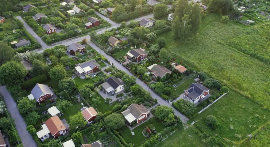 Malownicze ukształtowanie terenu z rzędem czerwonych domków i bujną zielenią.