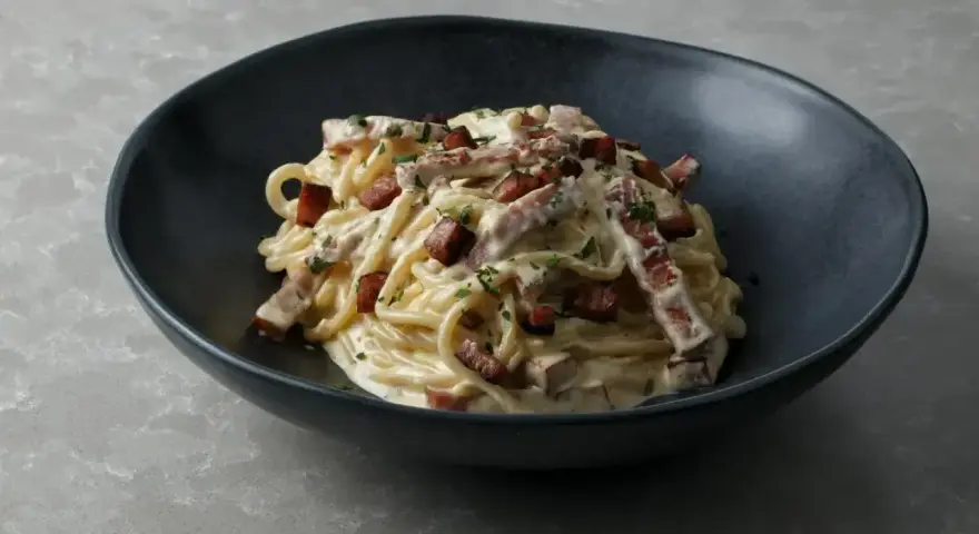 Pyszne spaghetti carbonara w ciemnej misce, idealne do nauki, jak zrobić carbonare.