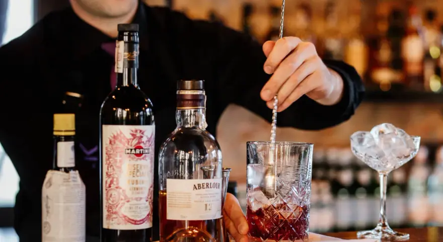 Barman miesza składniki na klasycznego Manhattan drinka. Obok butelki whisky Aberlour i Martini Riserva Speciale Rubino.
