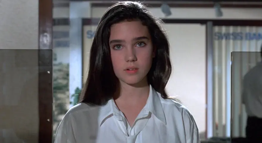 Młoda Jennifer Connelly w białej koszuli, z charakterystycznym spojrzeniem, jak z jej wczesnych filmów.