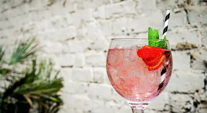 Orzeźwiający pink gin z lodem, truskawką i miętą, idealny na letnie popołudnie.