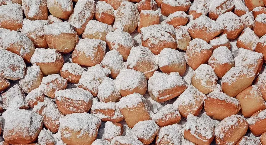 Ein Haufen goldbrauner, puderzuckerbestäubter Schmalzkuchen, die an ein schmalzkuchen originalrezept erinnern.