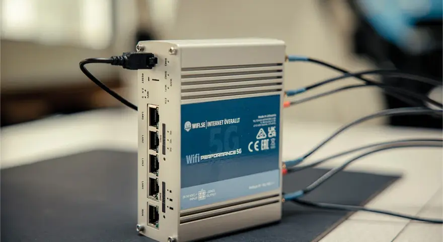 En silverfärgad 5G-router med flera LAN-portar och antennkablar. Perfekt för mobilt bredband i Europa.