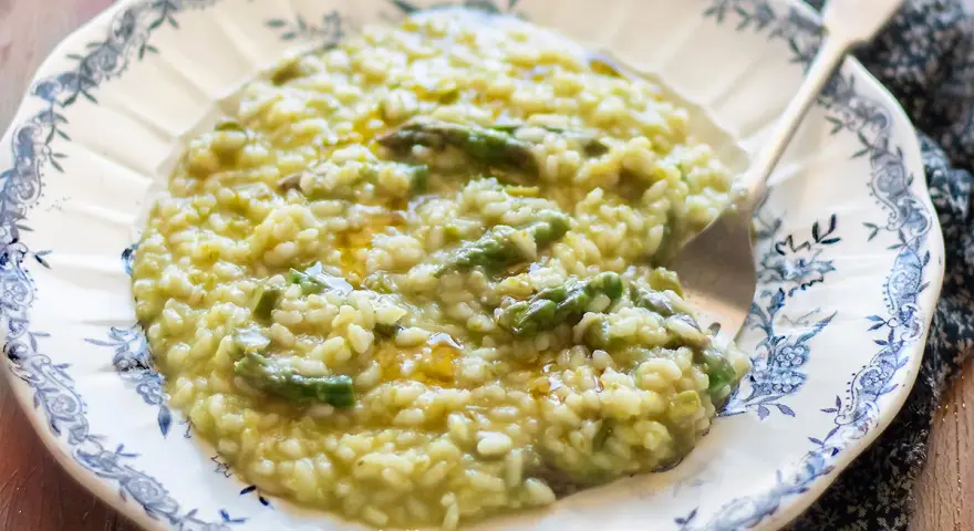 Un cremoso risotto agli asparagi, servito in un piatto decorato, pronto per essere gustato.