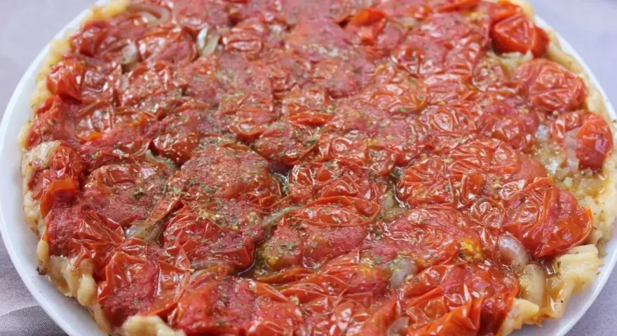 Tarte tatin di pomodorini confit, con cipolle caramellate e erbe aromatiche, un tripudio di sapori mediterranei.