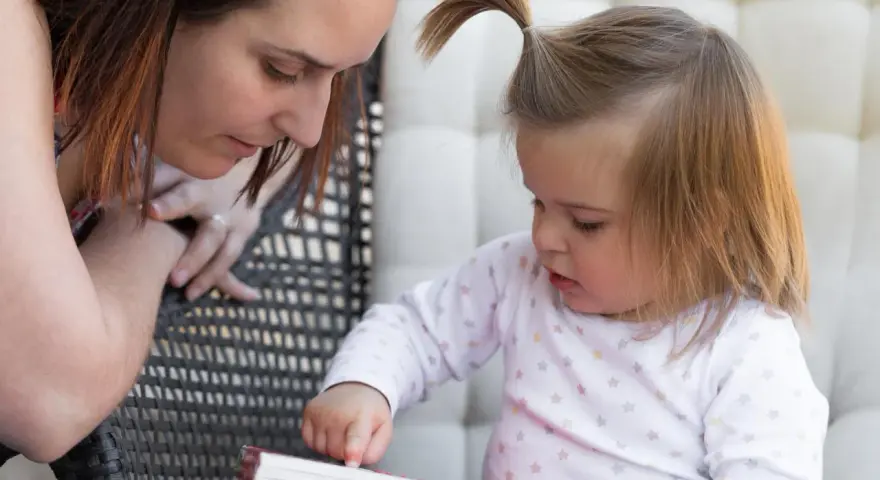 Mama czyta dziecku, a maluch odkrywa świat przez książkę, tworząc własne neologizmy dziecięce.