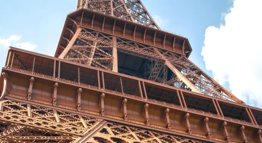 La famille Eiffel, une fortune bâtie sur le fer. Vue rapprochée de la Tour Eiffel, structure métallique complexe sous un ciel bleu.