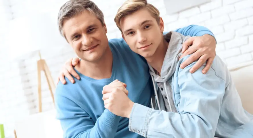 Ojciec obejmuje syna, wspierając go w ważnych życiowych rozmowach.