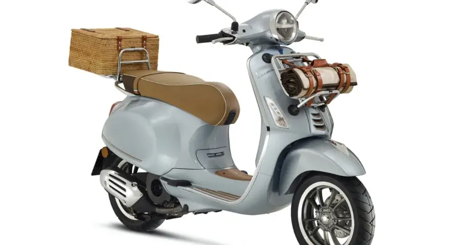 Stylowe skutery retro 125 w kolorze błękitnym, z wiklinowym koszem z tyłu i kocem z przodu, idealne na piknik.