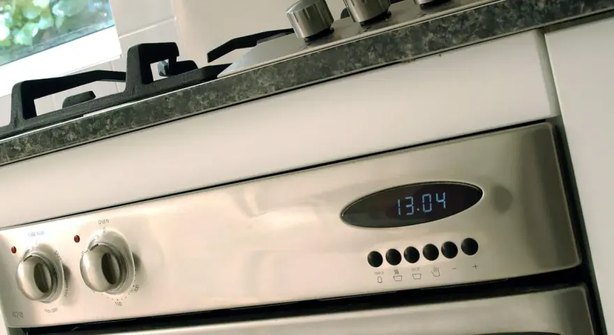 Edelstahl-Backofen mit digitaler Zeitanzeige (13:04). Die Knöpfe für Funktion und Temperatur sind sichtbar. Bereit für den ersten **Backofen einbrennen**.