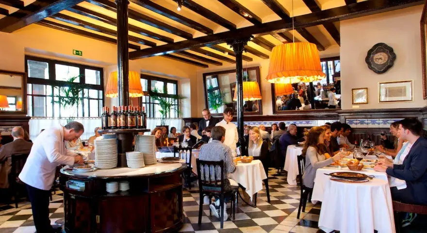 Un camarero prepara platos en un restaurante lleno de comensales. Los pasos para abrir un restaurante incluyen crear un ambiente acogedor como este.