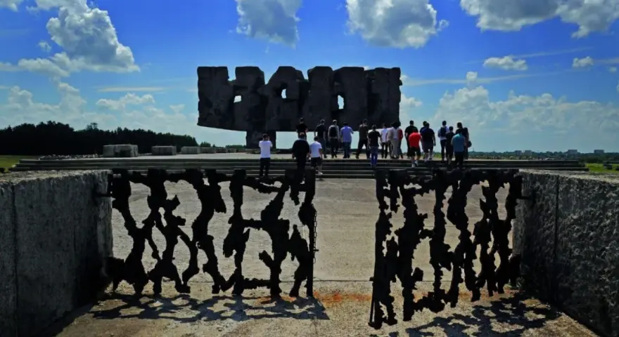 Brama pamięci na terenie byłego obozu Majdanek. Grupa ludzi zwiedza miejsce pamięci.
