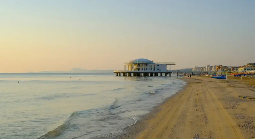 Alba dorata sul mare di Senigallia, con il celebre edificio sul mare e la spiaggia che si estende verso la città.