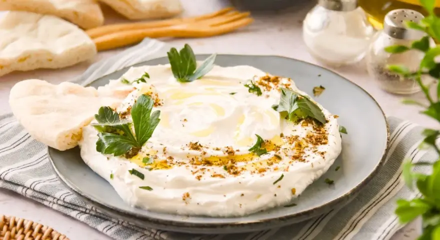 Labneh cremoso con aceite de oliva, za'atar y perejil, servido con pan de pita.