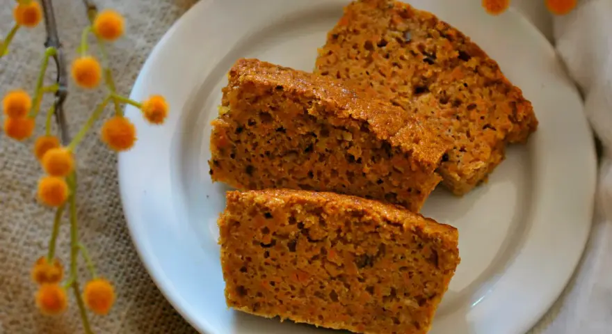 Rebanadas de bizcocho de zanahoria casero, esponjoso y con trocitos de zanahoria visibles, servidas en un plato blanco.