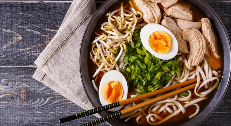 Pyszny shoyu ramen z kurczakiem, jajkiem na twardo, kiełkami fasoli mung i szczypiorkiem.