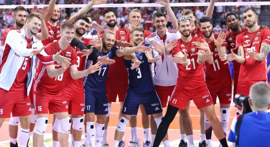 Uśmiechnięci siatkarze polski w czerwonych strojach pozują do zdjęcia, ciesząc się zwycięstwem.