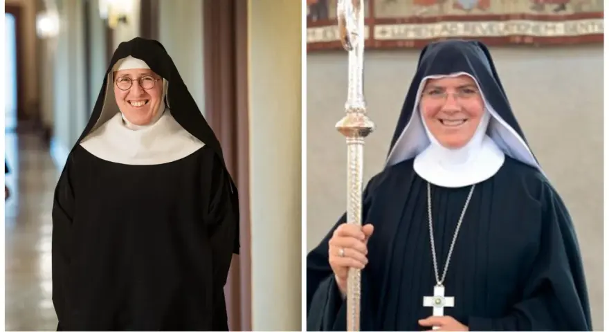 Two smiling nuns in traditional black habits and white wimples. This is what Catholic monks wear, along with a cross necklace and a staff.