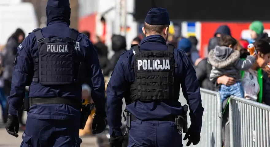 Dwóch policjantów w kamizelkach taktycznych pilnuje porządku. Chcesz wiedzieć, co trzeba zrobić, żeby zostać policjantem?