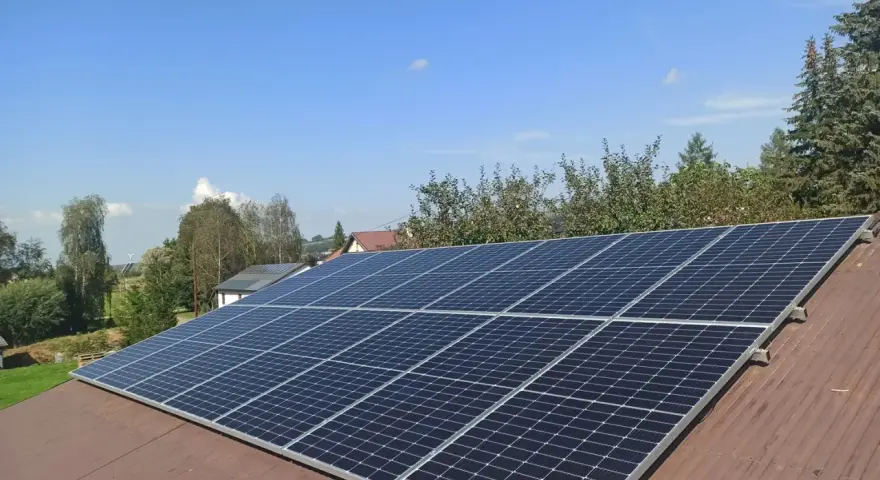 Panele fotowoltaiczne na dachu. Zastanawiasz się nad rozliczeniem rocznym czy miesięcznym? Słońce świeci, produkując czystą energię.