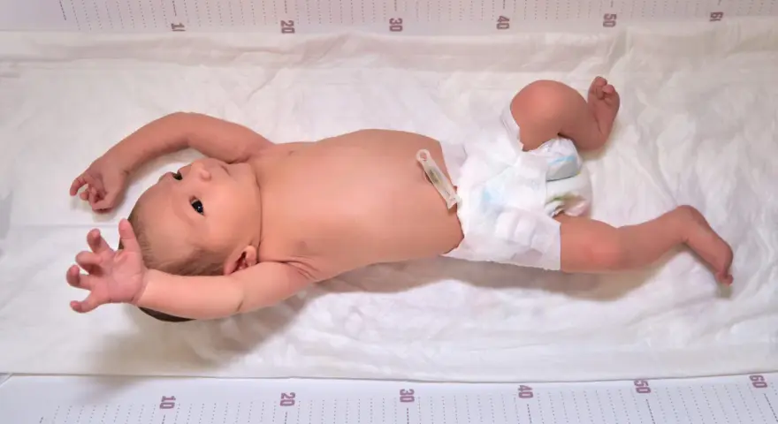 Niemowlę na macie z miarką, wyciąga rączki. Czy to odruch moro, czy objaw padaczki?