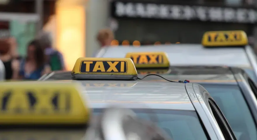 Reihe von Taxis mit gelben Dachschildern. Die aktuellen Taxipreise sind auf den Schildern nicht sichtbar, aber die Fahrzeuge stehen bereit.
