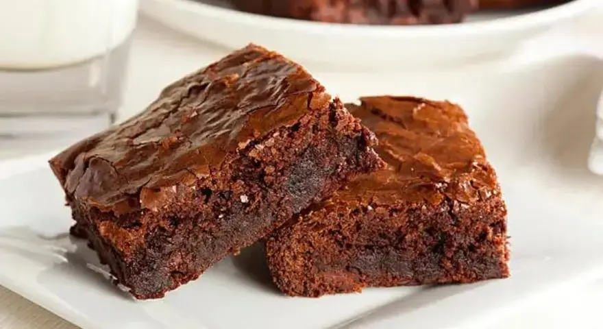 Dos deliciosos trozos de brownie de chocolate, con una textura húmeda y crujiente por encima, listos para ser disfrutados.
