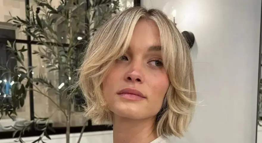 Kobieta z blond włosami w stylu cienkie włosy bob warstwowy cieniowany, z delikatnymi falami i grzywką na bok.