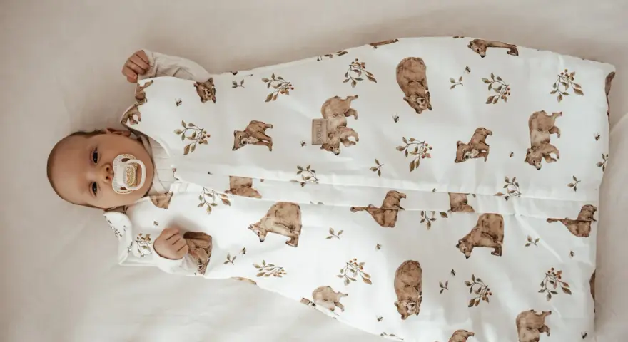 Niemowlę w śpiworku z misiami i pszczołami. Od kiedy kołderka dla niemowlaka jest tak urocza, sen staje się przyjemnością.