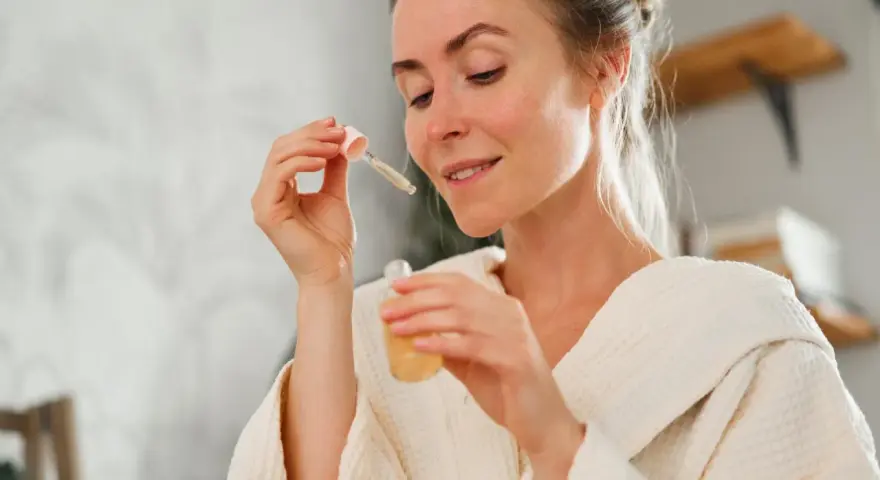 Frau mit einem Tropfen Serum in der Pipette, bereit für ihre Hautpflege-Routine. Ob Retinol oder Hyaluron, sie wählt das Beste für ihre Haut.