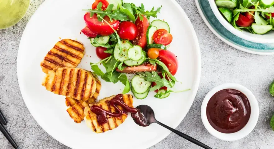 Grillowany ser halloumi z sosem barbecue i świeżą sałatką z pomidorów i ogórków. Idealny pomysł na lekki obiad.