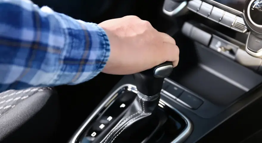 Dłoń na dźwigni zmiany biegów w aucie z funkcją auto hold i manualną skrzynią.