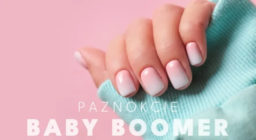Dłoń z paznokciami hybryda baby boomer w delikatnym różowo-białym ombre, na tle pudrowego różu i turkusowego materiału.