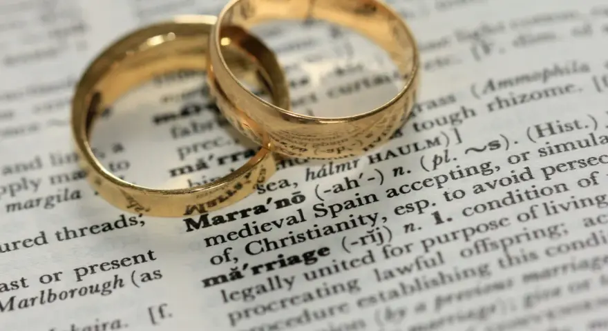 Two gold wedding rings rest on a dictionary page, highlighting the definition of "marriage" and its contrast to sexual immorality.