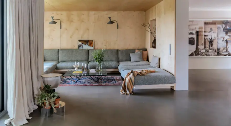 Sofá modular gris, alfombra oriental, mesa de centro de cristal y detalles de interiorismo años 60.