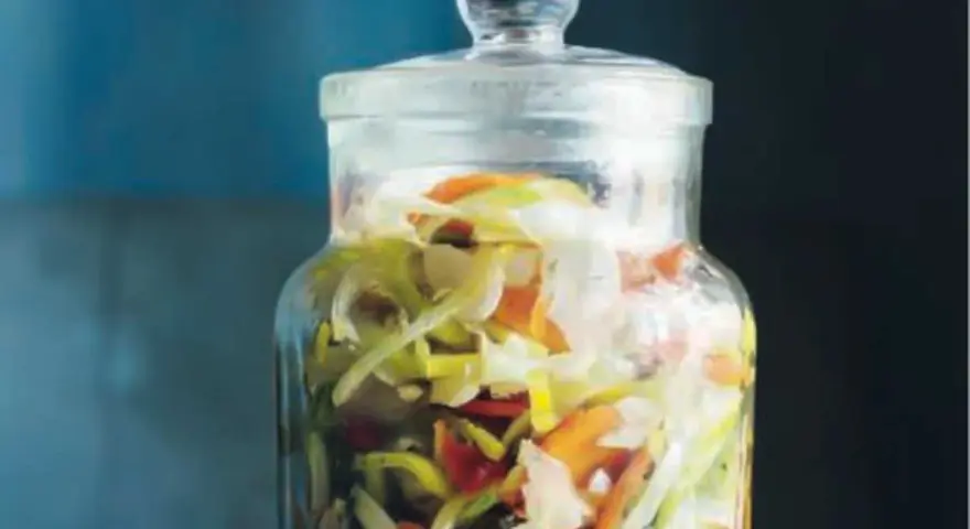En glasburk fylld med strimlad vitkål, morötter och purjolök, redo för en 3 veckors sallad.