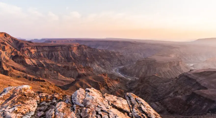 Wąwóz Fish River w Namibii, z rzeką wijącą się w dole. Zachodzące słońce maluje skały na ciepłe barwy.