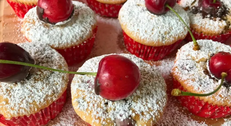 Saftige kirsch muffins, bestäubt mit Puderzucker und garniert mit frischen Kirschen. Ein süßer Genuss!