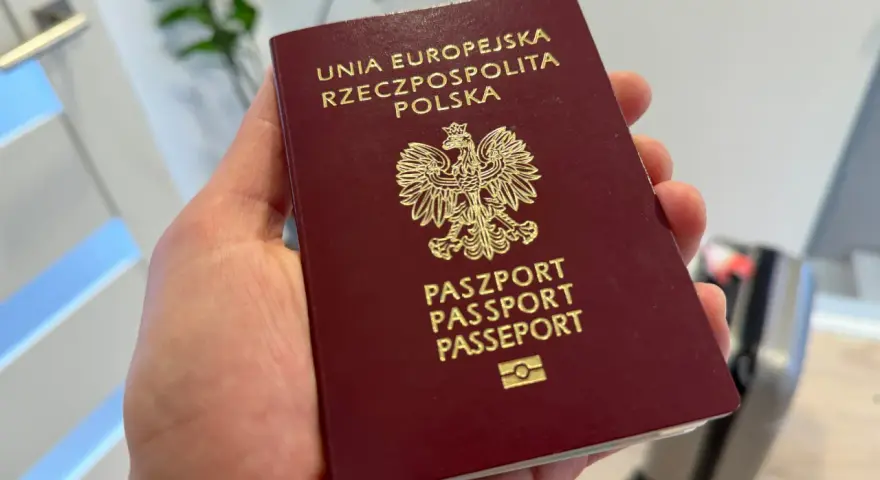 Polski paszport w dłoni. Czy do USA potrzebna jest wiza? Podróż w toku, walizka czeka.