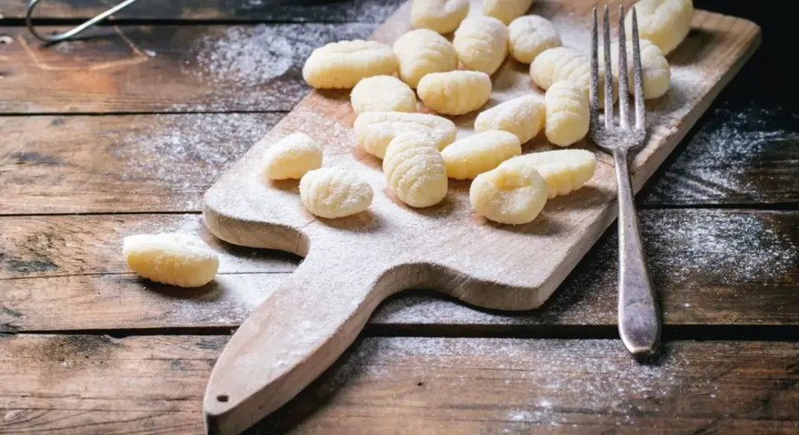 Gnocchi fatti in casa su tagliere di legno, spolverati di farina. L'impasto gnocchi troppo appiccicoso ha reso la preparazione un po' complicata, ma il risultato è invitante.