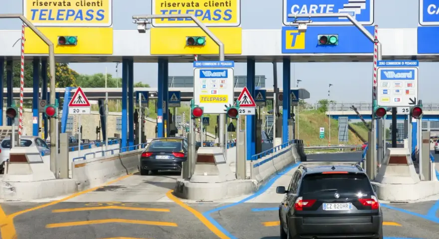 Casello autostradale con corsie Telepass e carte. Un'auto nera attende, forse per un mancato pagamento Telepass senza ricevuta.