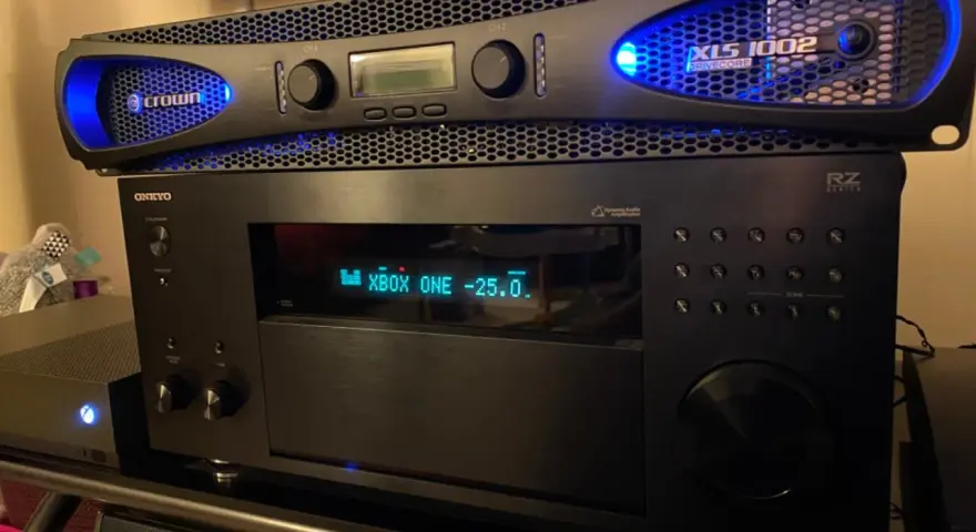 Wzmacniacz Crown XLS 1002 z niebieskim podświetleniem, umieszczony nad amplitunerem Onkyo.