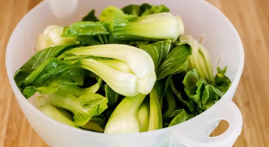 Frischer Pak Choi in einem Sieb, bereit zum rohen Essen. Knackig und grün, eine gesunde Ergänzung für jede Mahlzeit.