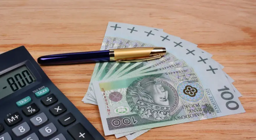 Kalkulator, długopis i banknoty 100 zł. Szukasz, który bank ma najwyższe oprocentowanie lokat na 3 miesiące?