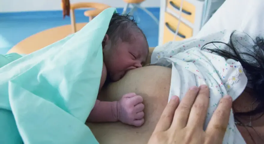 Neugeborenes Baby an der Brust der Mutter, ein Moment der stillen Geburt und des ersten Kontakts.