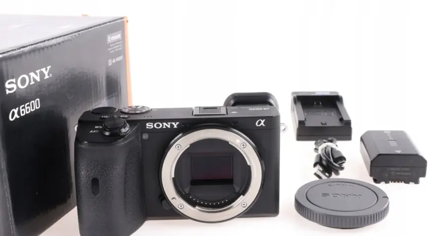 Aparat Sony Alpha 6600 z akcesoriami: pudełko, ładowarka, bateria, kabel i dekielek.