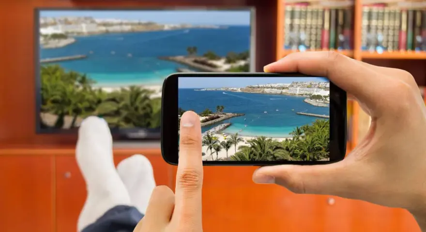 Jak podłączyć telefon do telewizora przez HDMI? Widok na plażę z palemami na ekranie telefonu i telewizora.